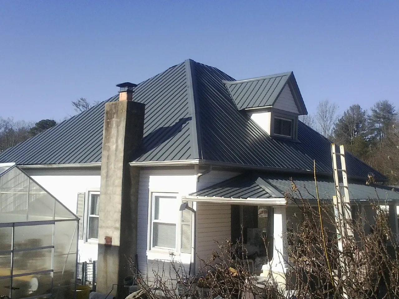 Dark blue standing seam metal roof on a white farmhouse with dormer — Slate & Tile Roof Repair by Roofing Brothers in York Beach