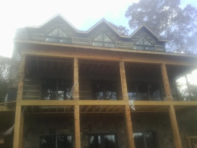 Dormers and porch framing on a large log home under construction — Roof Coating work by our crew in York Beach