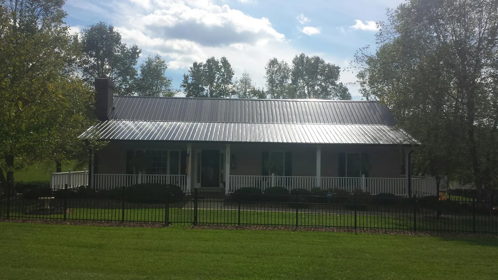 Gray metal roof on a brick ranch with a full width front porch — Gutter Guard Installation work by our crew in York Beach