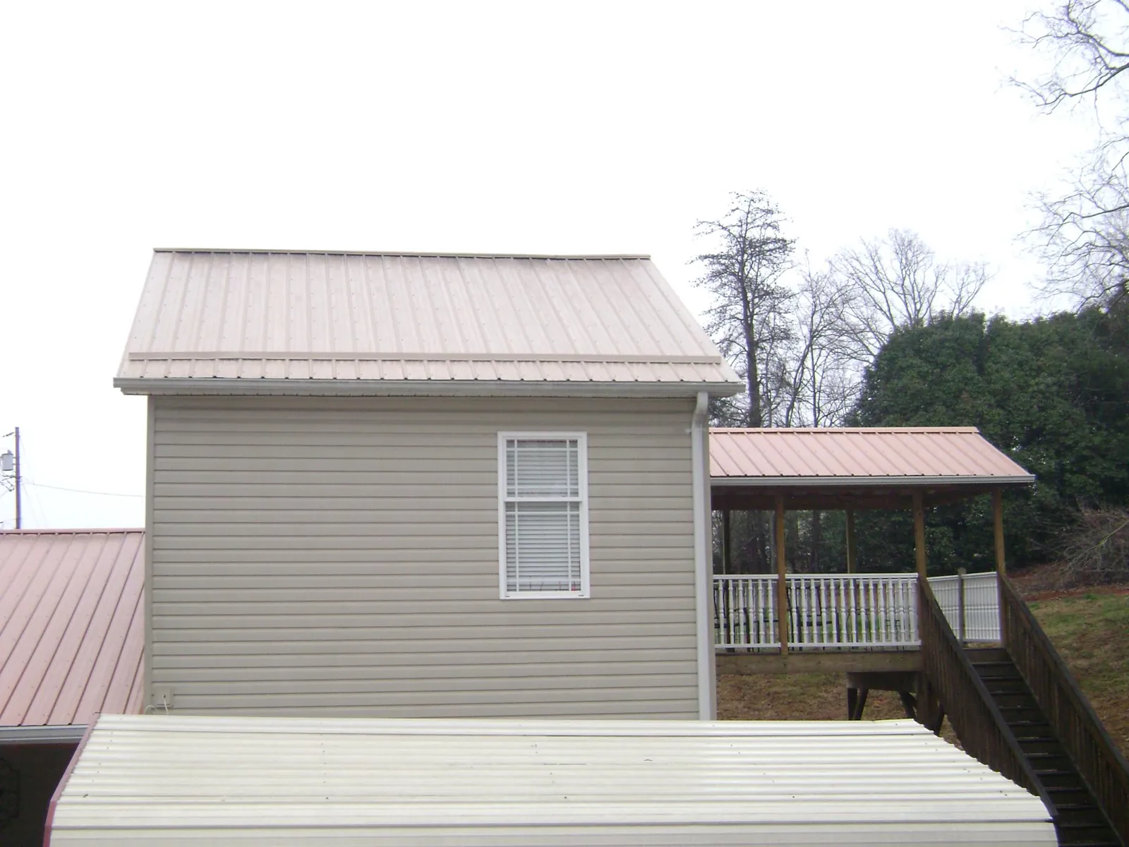 Tan metal roofs on a two story addition and attached porch, from a Roof Replacement job in York Beach